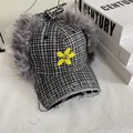 Dettaglio del cappello a quadri con paraorecchie in pelliccia e ricamo a fiori - M / Quadri Neri