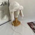 Detail of white winter trapper hat with soft faux fur lining on a wooden display stand - M (56-58cm) / White