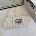 Detalle del bordado de tres osos y texto en el gorro de punto de color beige - M (56-58cm) / Blanco