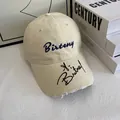 Close-up of beige baseball cap featuring Birteny embroidery and distressed brim details - M / Off White