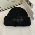 Detalle del gorro de punto acanalado negro con tres parches de estrellas de cuero en el dobladillo - M / Negro