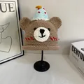 Close-up of handmade brown knit bear hat with blue festive cone topper on a display stand - M(56-58cm) / Khaki
