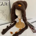 Detail van pluche wintermuts met zacht materiaal en opvallende oranje pluizige bollen - M (56-58cm) / koffiekleur