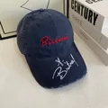 Close-up of distressed navy baseball cap with red embroidery and white brim signature - M / Navy Blue