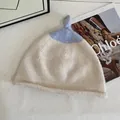 Detailed view of cream knit beanie with blue contrast knot and soft wool texture - M (56-58cm) / Off White