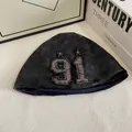 Dettaglio del berretto in velluto grigio con ricamo patch 91 e bordi sfrangiati vintage - M / Nero