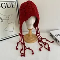 Detail of red handmade crochet knit trapper hat with ear flaps and tassels on model head - M(56-58cm) / Red