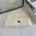 Dettaglio del berretto in maglia crema con design usurato e ricamo a cane blu - Bianco