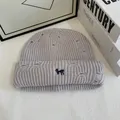 Dettaglio ravvicinato del berretto in maglia grigio chiaro con ricamo cane blu e fori in stile used - Bianco Grigiastro