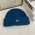 Detailed knit texture of blue distressed beanie with white animal embroidery detail - Teal