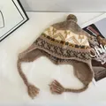 Detail van gebreide Fair Isle-muts met oorklappen, kwastjes en een zachte pompon - M (56-58cm) / Khaki