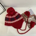 Close-up of red Fair Isle knit hat featuring winter snowflake patterns and plush pom-poms - M / Red