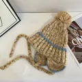 Flat lay of a warm knit beanie with pom-pom, earflaps and colorful mixed yarn details - M (56-58cm) / Khaki
