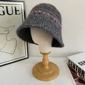 Detail of grey Fair Isle knit bucket hat with ethnic patterns on a wooden mannequin - M (56-58cm) / Gray