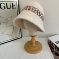 Detailansicht eines Fair-Isle-Strickhuts mit geometrischen Mustern auf einem Holzständer - M / Gebrochenes Weiß