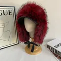 Detalle de gorro de invierno de piel sintética roja con ala de cuero y lazo de seda negro - Burdeos