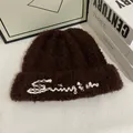 Detalle del gorro de punto de felpa marrón oscuro con bordado Sunrise blanco y textura suave - M / Café
