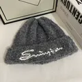 Detalle macro del gorro sherpa gris oscuro con bordado Swing blanco y textura rizada - M / Gris oscuro