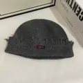 Detalle de gorro de punto gris oscuro con bordes deshilachados y etiqueta de tela roja - M (56-58cm) / Gris oscuro