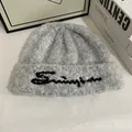 Detalle del gorro de punto gris con textura de felpa suave y bordado cursivo - M / Gris claro