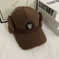 Detail of brown faux shearling trapper hat featuring a warm earflap design and 'U' badge - M (56-58cm) / Coffee