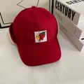 Detail of red winter baseball cap with plush earflaps and cute fruit embroidery - M (56-58cm) / Red