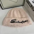 Detalle del gorro de punto rosa suave con bordado negro y textura de lana rizada - M / Rosa