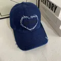Dettaglio del cappellino in denim blu con ricamo a cuore e texture vintage invecchiata - M (56-58cm) / Blu scuro