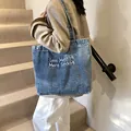 Blue denim tote bag with Less Mondays More Sundays text shown on a model - Style 2 Light Blue (Less Mondays Embroidery)