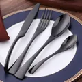 Modern 4-piece black stainless steel cutlery set with matte handle on ceramic plate - Black