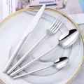 Polished silver stainless steel cutlery set with V-shaped handles on a white plate - Silver