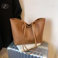 Caramel brown large tote bag with lychee grain texture placed on a silver suitcase - Brown