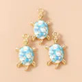 Macro shot of three golden sea turtle charms with blue and white enamel for DIY jewelry - Light Blue Turtle