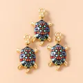 Detailed close-up of colorful enamel turtle pendants with gold frames and DIY hanging loops - Geometric Color Block (3195) / Black and Blue Gradient Turtle
