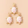 Detailed view of sea turtle pendants with pink cherry blossom enamel on gold metal base - Cherry Blossom Pattern (3195) / Pink Turtle