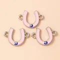 Macro detail of three pink enamel horseshoe charms with evil eye motifs for jewelry DIY - Silver Pink