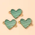 Macro-opname van groen-witte emaille hartconnectoren voor DIY-sieraden met twee ophangringen - 10 Stuks/Verpakking / Goud en Groen