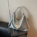 Silberne Metallic-Tragetasche mit Schmetterlingsschnalle und Perlenkette auf Stuhl - 30cmx24cmx9cm / Silber