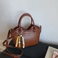 Bolso tipo cubo trenzado marrón con colgante de cuentas y correa ajustable - Marrón Con Colgante de Cuentas de Madera