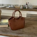 Brown woven bucket bag with circular handles on a wooden table in a kitchen setting - Brown No Pendant