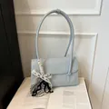 Light blue faux leather underarm bag with ribbon pendant on vintage book background - Blue
