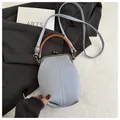 Detail of light blue crossbody bag with brown round handle and metal kiss-lock closure - Gray