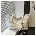 Détail du sac cabas blanc texturé avec motifs de nœuds noirs posé sur un rebord de fenêtre - Blanc