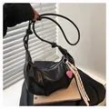Detail of black pleated croissant bag featuring embossed FASHION logo and heart pendant - No Pendant / Black