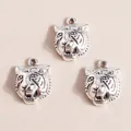 Three antique silver tiger head charms for DIY jewelry making on a beige background - Antique Silver