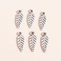 Detail view of vintage silver alloy feather pendants with intricate leaf vein textures - Antique Silver