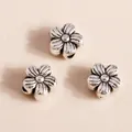 Detailed macro view of vintage silver flower charms with intricate petal texture for DIY jewelry - Antique Silver