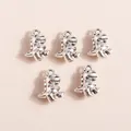 Five vintage silver alloy dinosaur charms for DIY jewelry making on a pink background - Silver