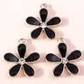 Macro detail of three gold-plated cherry blossom charms with black enamel and rhinestones - Black