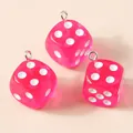 Close-up of translucent pink acrylic dice pendants with silver metal loops for DIY crafts - Pink